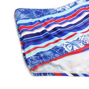 Macro detail of men's swim trunks featuring blue floral patterns and red striped patterns