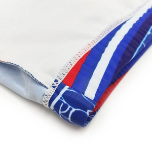 Detail of red and blue striped ribbon and blue water pattern on white swimming trunks