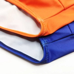 Detail of double-needle stitching on vibrant orange and blue striped swim trunks
