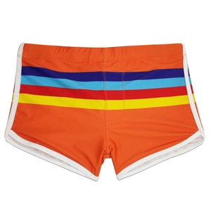 Detail of orange men's swim trunks featuring vibrant rainbow stripes and white piping trim