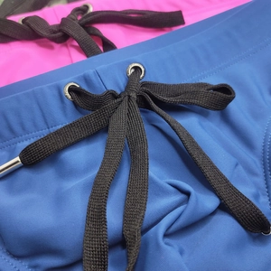 Detail of blue and pink men's swim briefs showing woven drawstring and metal eyelets