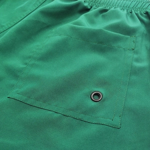 Detail of green quick-dry sports shorts showing rear pocket stitching and metal eyelet