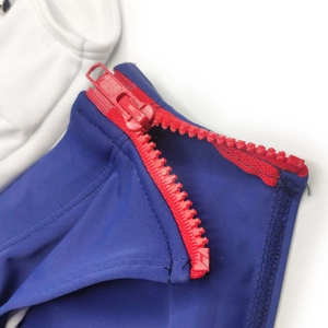 Close-up of contrast red plastic zipper detail on navy blue stretchy swimwear fabric
