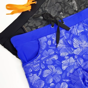Close-up of metallic hibiscus print and side pockets on men's swim trunks with drawstring