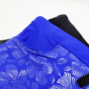 Detailed view of blue men's swim trunks with silver floral relief print and elastic fabric