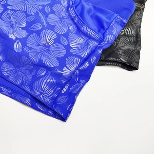 Close-up of metallic hibiscus floral print on blue and black swim trunks fabric