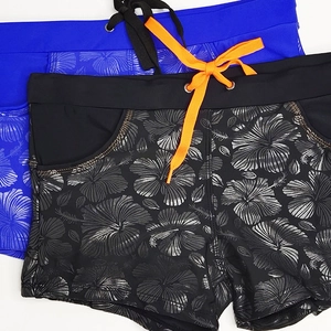 Detail of blue and black swim trunks with floral embossed print and side pockets