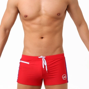 Detail of red swimming trunks with zipper pocket, drawstring waist and side stripes