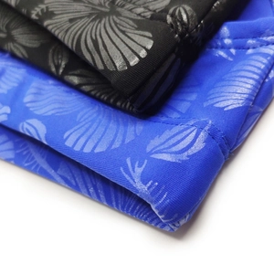 Close-up of swim briefs featuring silver metallic shell and tropical floral patterns