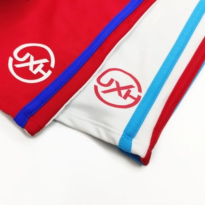 Detail of color block swim trunks featuring three-color side stripes and printed JX logo