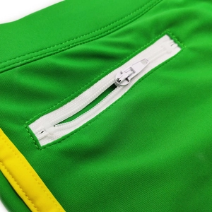 Detail of green swim shorts featuring a hidden white zipper pocket and yellow piping