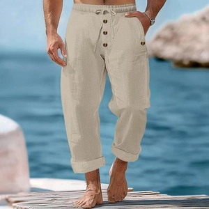 Men's loose linen drawstring trousers in beige with button fly detail by the sea