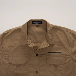 Detail view of khaki cotton work shirt showing chest pockets and embroidery brand label