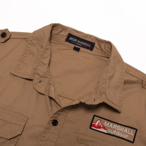 Close-up of khaki cotton outdoor shirt featuring shoulder epaulettes and chest pocket patches