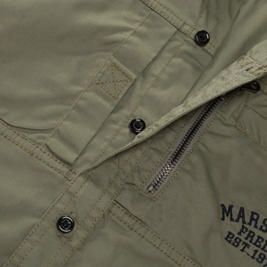Macro shot of durable olive green military shirt featuring zipper and logo embroidery
