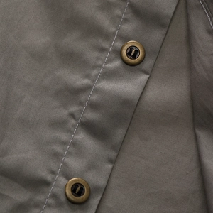 Close-up of military style olive grey cotton shirt showing copper buttons and stitching