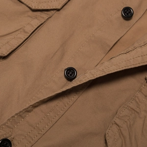 Detail of khaki cotton shirt with durable twill texture and black resin button accents