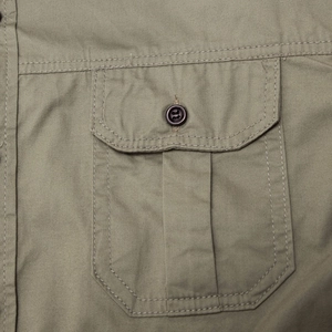 Detail of olive green cotton military shirt showing the buttoned chest pocket with pleats