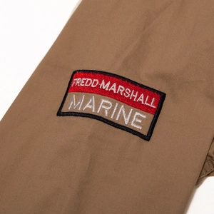Detail of khaki cotton shirt sleeve featuring Fredd Marshall brand embroidery patch