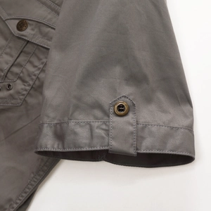 Close-up of grey military shirt with durable twill fabric and vintage bronze buttons