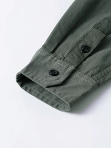 Detailed close-up of olive green work shirt cuff with double buttons and contrast stitching