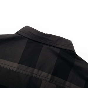 Gros plan sur le col et les coutures de cette chemise en coton à carreaux noirs et gris