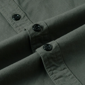 Close-up of olive green cotton work shirt showing detailed stitching and black buttons