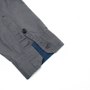 Detail of gray cotton shirt cuff with dark button and navy twill lining accent