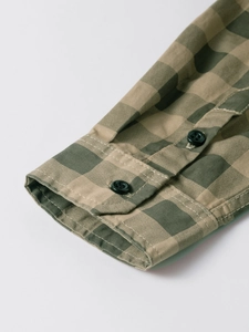 Close-up of the adjustable buttoned cuff on this olive and tan plaid cotton shirt