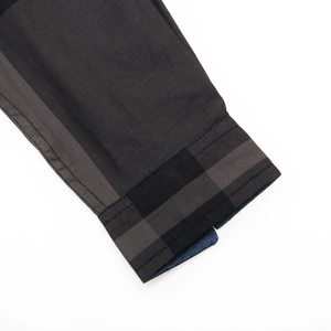 Détail du poignet de chemise en coton avec doublure intérieure à carreaux gris et noir