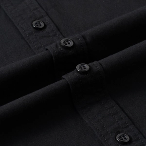 Detailed close-up of black cotton shirt fabric with button accents and neat stitching