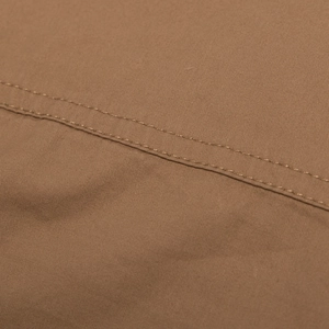 Detailed macro view of heavy-duty double stitching on brown cotton cargo shirt fabric