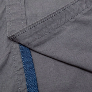 Macro detail of high-quality cotton fabric stitching and blue contrast inner placket ribbon