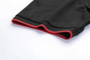Dettaglio della manica polo nera con polsino a coste rosse e trama piqué traspirante