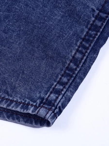Detail of vintage blue cotton denim shirt cuff with orange double stitching and stone wash