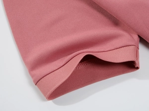 Detail view of pink polo shirt sleeve featuring ribbed cuffs and pique cotton texture