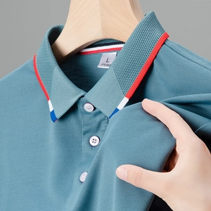 Dettaglio della polo blu con colletto a righe tricolori e tessuto in cotone piquet