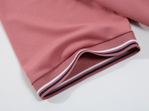 Detail of piqué fabric polo shirt sleeve with ribbed navy and white striped cuffs