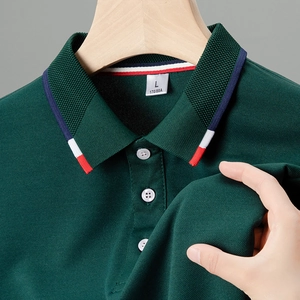 Dettaglio del tessuto polo verde scuro con colletto a righe tricolore e bottoni bianchi