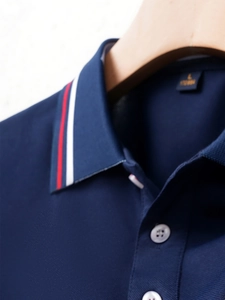 Close-up of navy piqué polo shirt collar with red and white striped tipping detail