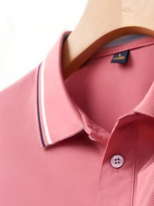 Close-up of coral pink pique polo shirt collar with navy blue and white striped edges
