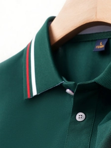 Detail of dark green polo shirt featuring a striped collar and breathable pique fabric