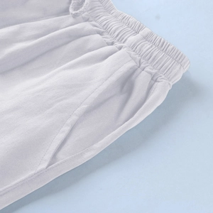 Detail of white linen beach shorts featuring elastic waistband and side pockets