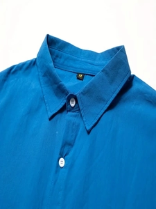 Detail of the navy blue cotton linen shirt collar featuring white resin buttons and M label