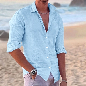 Close-up detail of light blue men's linen shirt with wood buttons in a beach setting