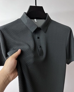 Gros plan du polo en soie glacée gris foncé montrant la texture du tissu tressé 3D
