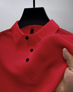 Détail du polo en soie glacée rouge montrant la texture 3D et la patte à trois boutons