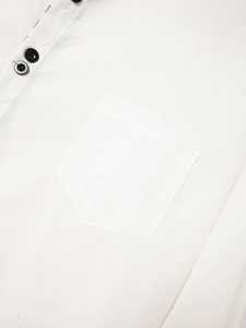 Detail of men's white shirt featuring black buttons and a front chest pocket design