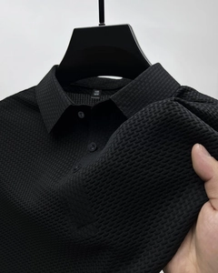 Vue détaillée de la texture gaufrée 3D et de la patte à trois boutons du polo noir pour homme