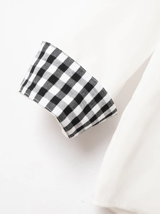 Detailed macro shot of white shirt sleeve cuff featuring black gingham check pattern contrast